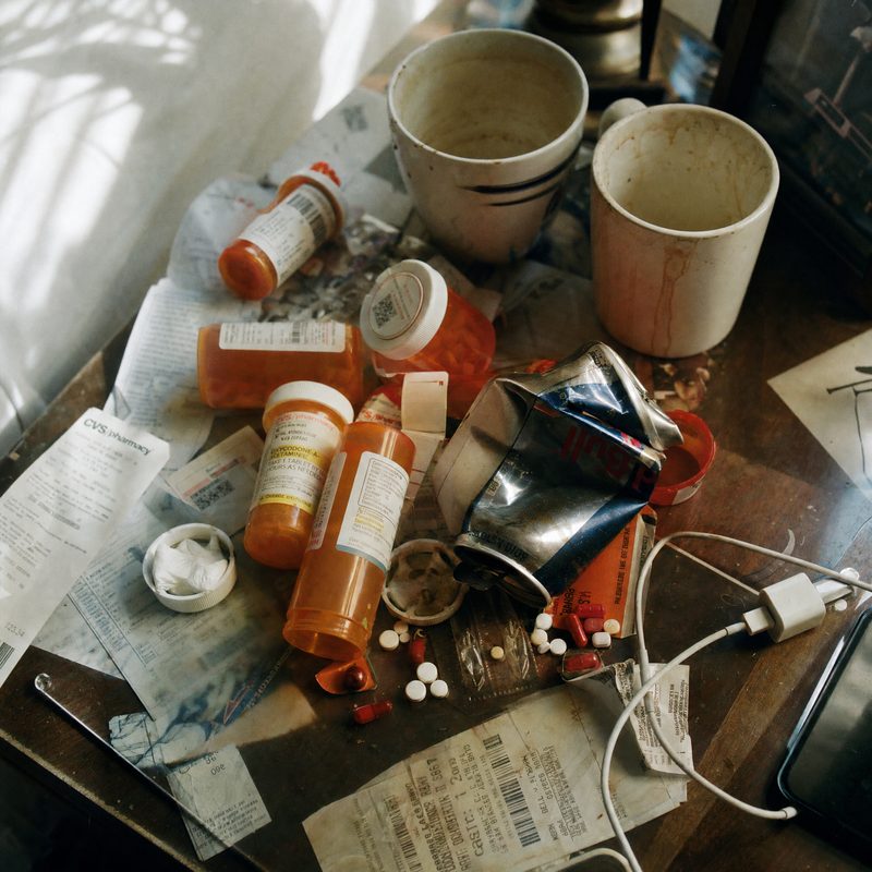 Messy desk with prescription pill bottles and coffee cups